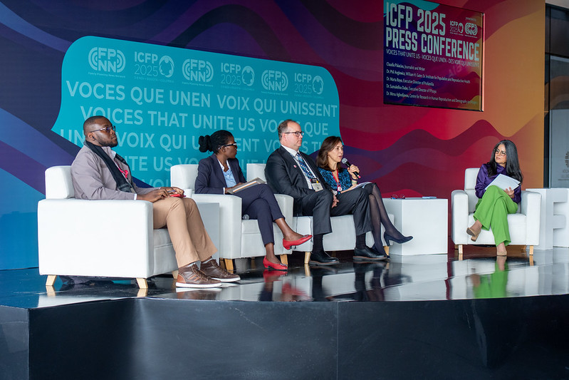 Five people sit on a stage for a live interview with a journalist
