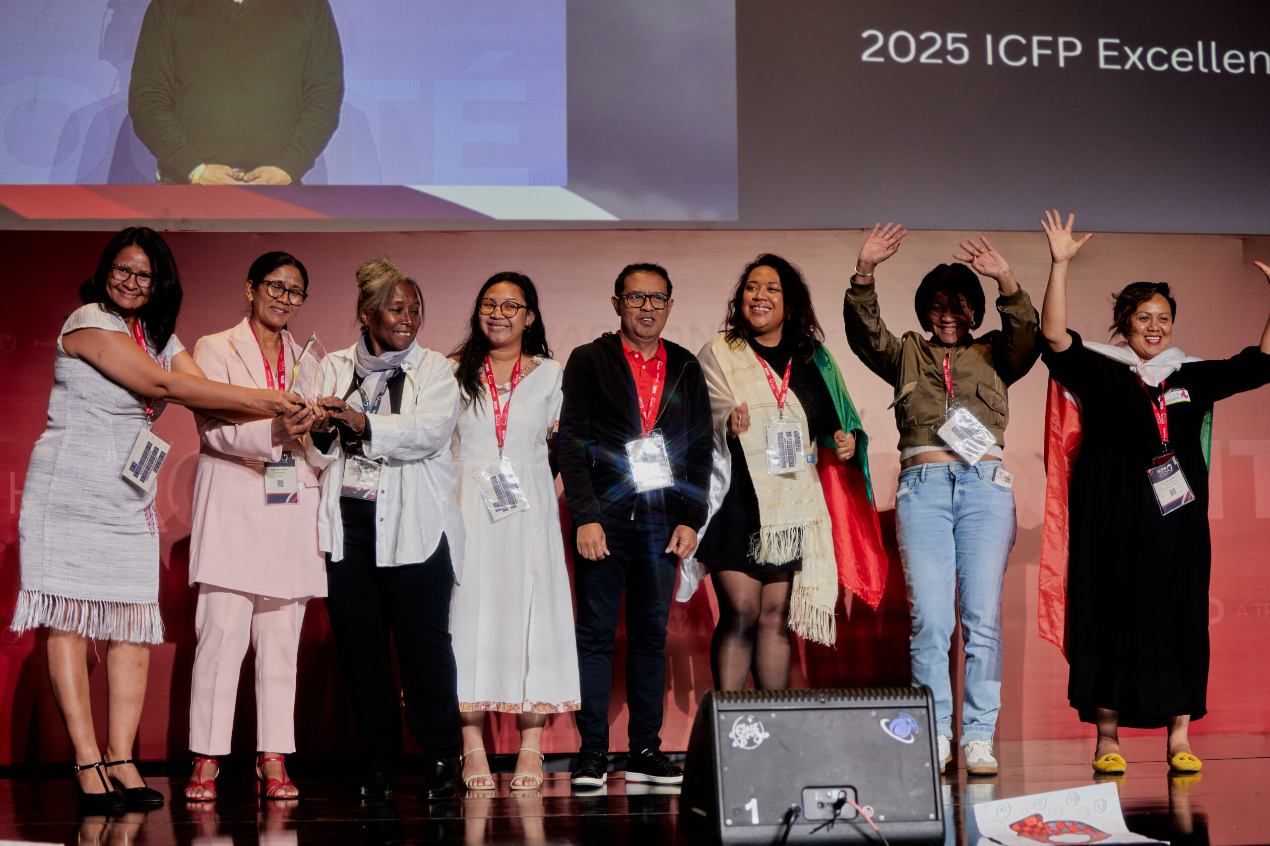 Un groupe de personnes sur scène, les bras tendus, tenant leur récompense.