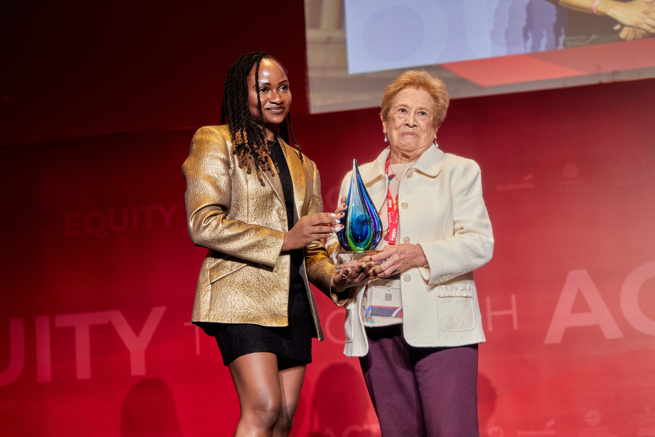 Une femme recevant un prix des mains d'une autre femme sur scène