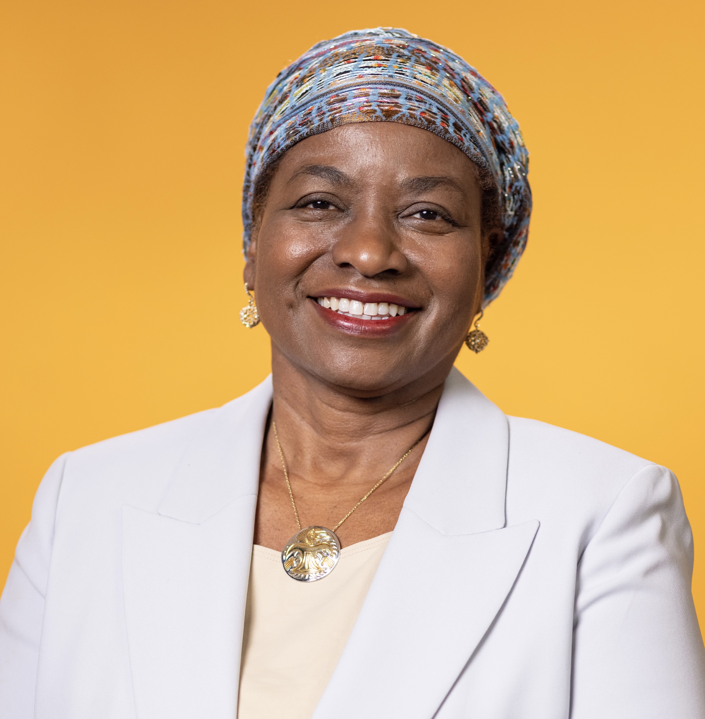 Portrait d'une femme sur fond jaune, vêtue d'un blazer blanc